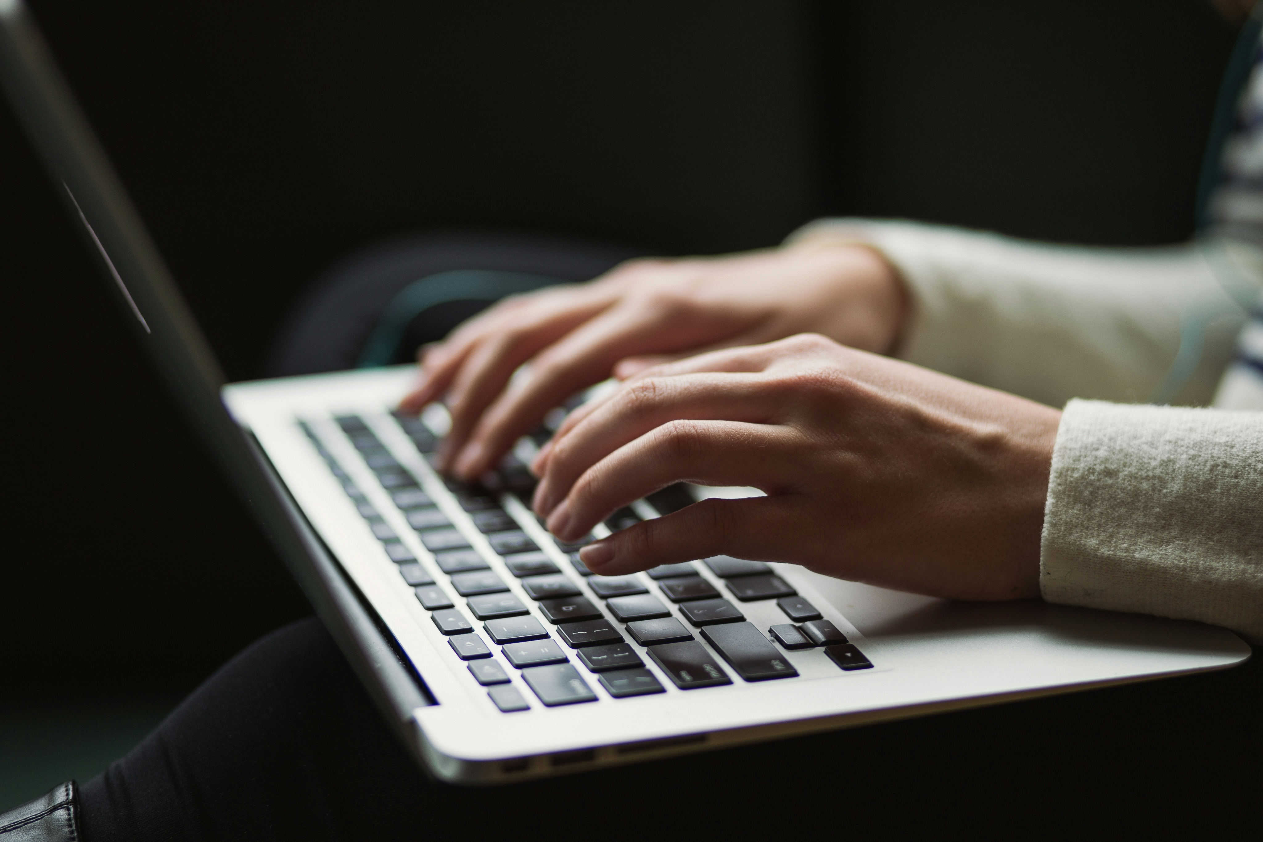 Hands typing a message on a laptop